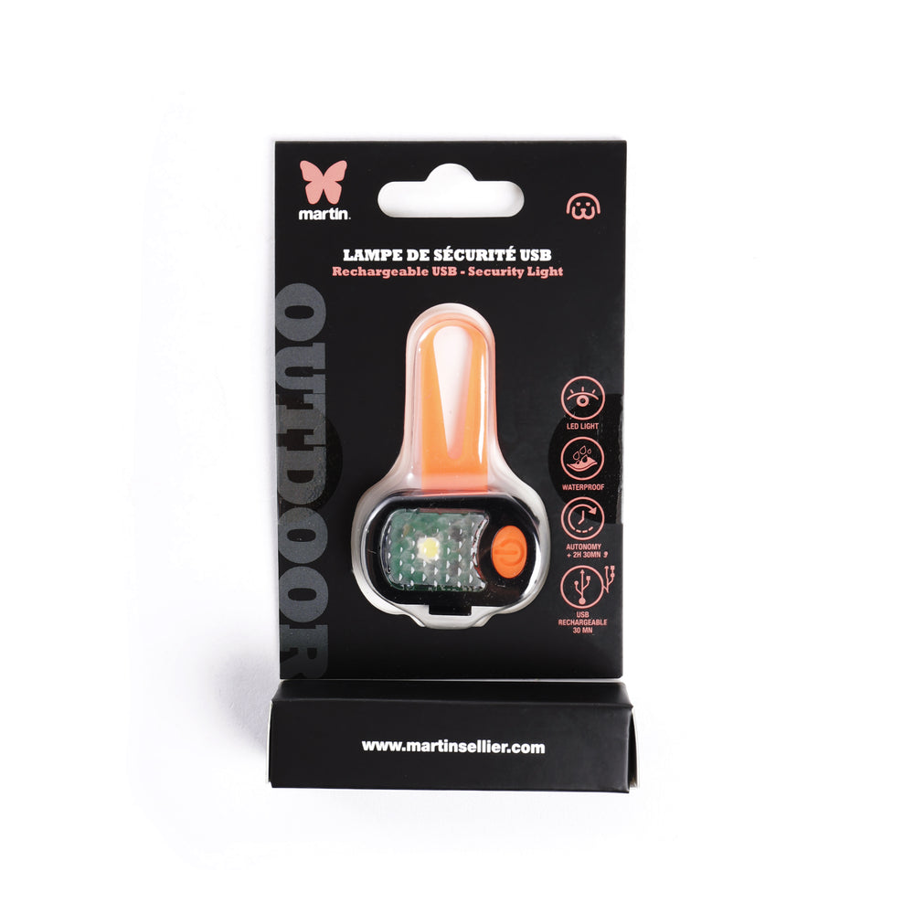 ámpara de seguridad LED para perros en color naranja, mostrada en su envase original de Martin Sellier. Luz recargable por USB, resistente al agua y con sistema de enganche para collar, arnés o correa. Perfecta para mejorar la visibilidad en paseos nocturnos.