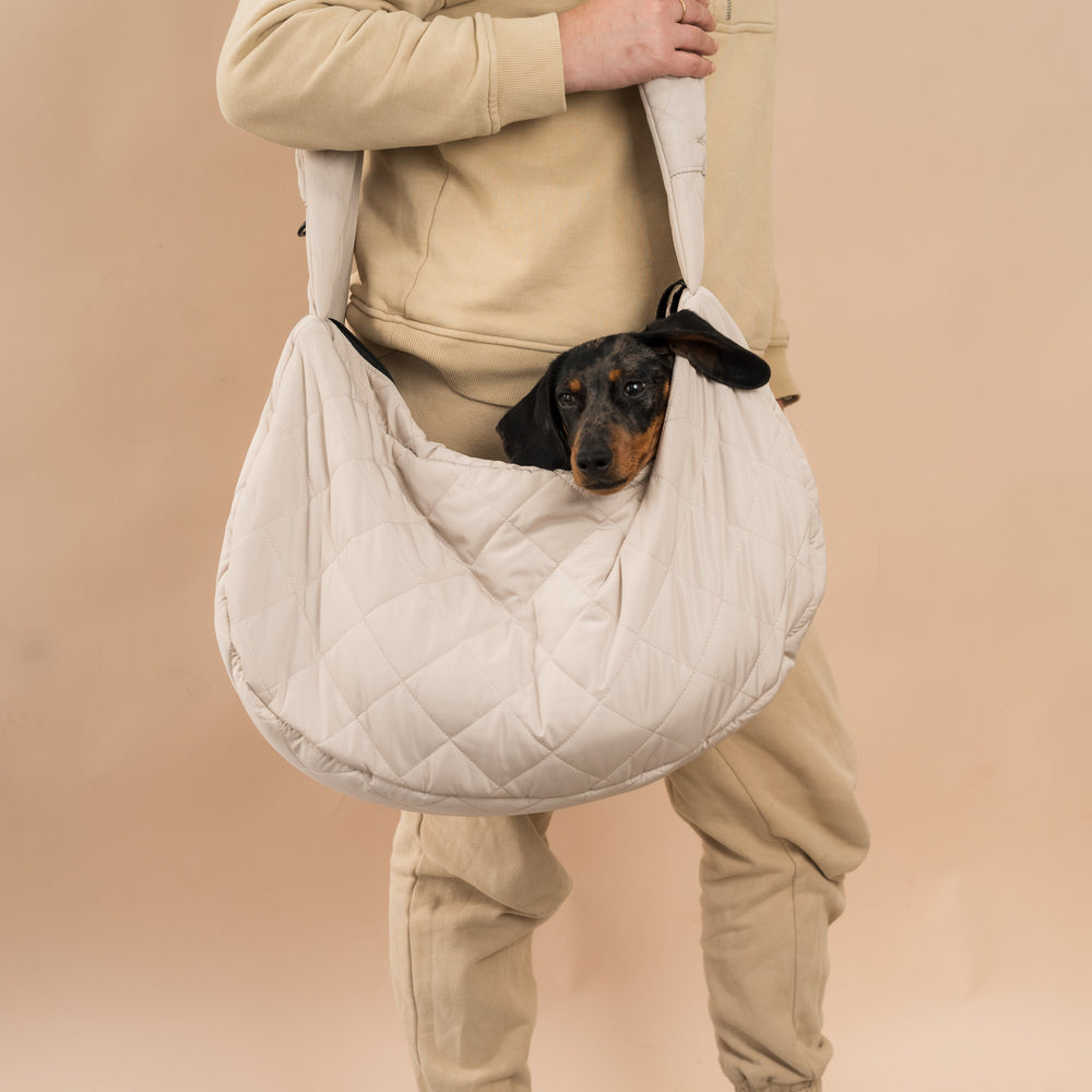 persona con bolso bandolera color beix con teckel tumbado comodamente dentro