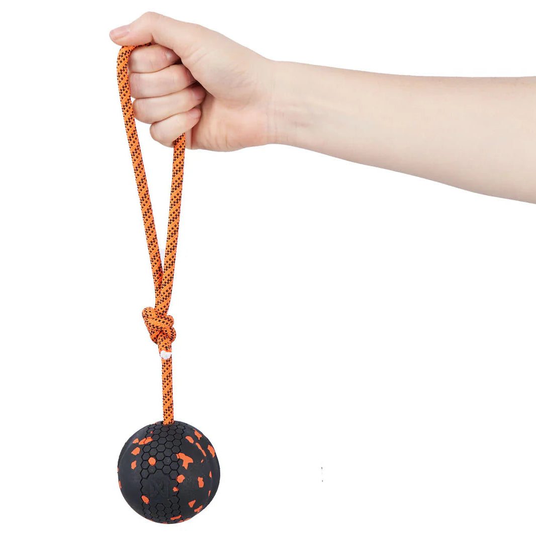 Pelota ultrarresistente Dog Ball on Rope de Non-stop Dogwear en color naranja y negro con cuerda reciclada para lanzar y jugar al tira y afloja.